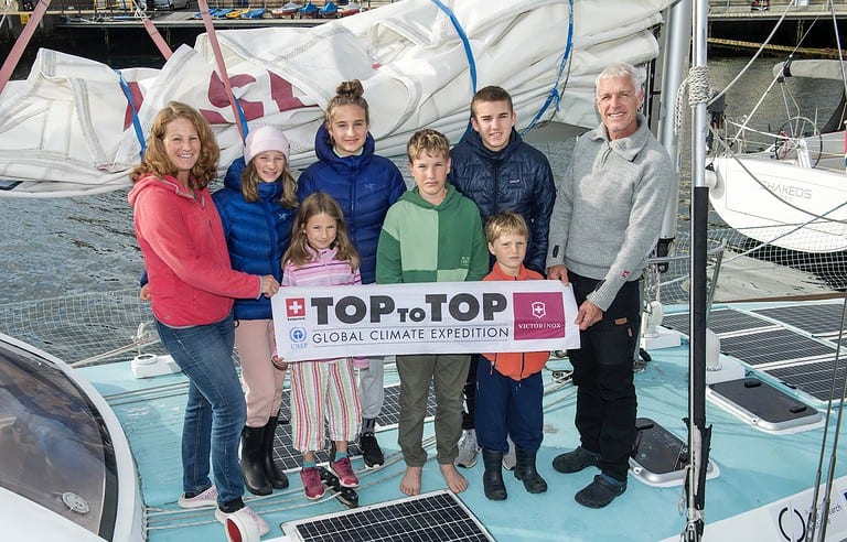 Swiss climate campaigners and their six children on he boat holding their charity Top to Top banner