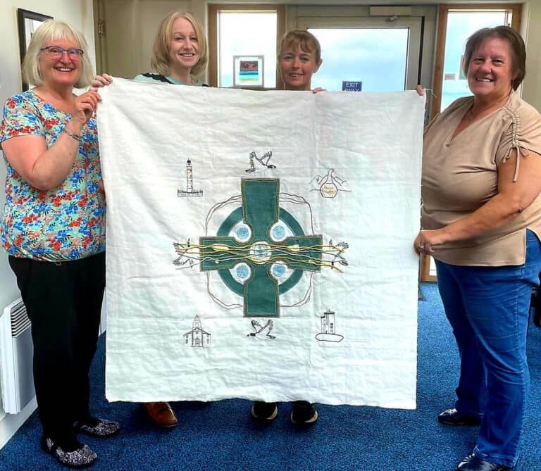 A panel of The Spirit of the Highlands and Islands Tapestry with stitchers in Islay