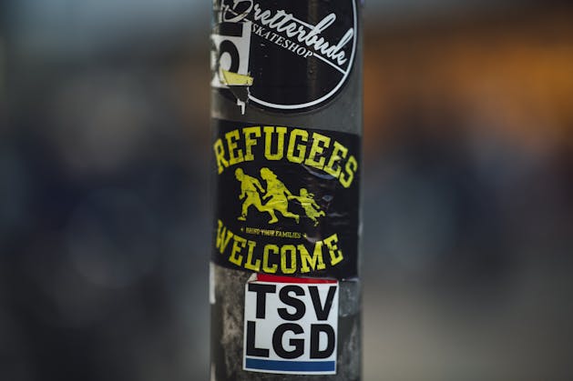 Photo: Street pole with stickers including 'Refugees Welcome', a message of acceptance and solidarity. Credit: Markus Spiske