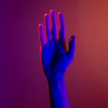 A single hand under neon lighting creating a colorful visual effect by cottonbro studio