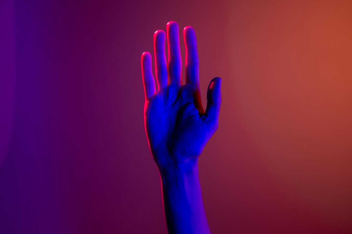 A single hand under neon lighting creating a colorful visual effect by cottonbro studio