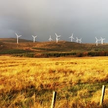 Wind turbines in Claonaig, Scotland, showcasing renewable energy amidst lush fields.