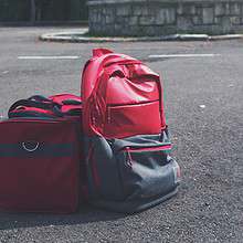 Red backpack and matching bag on asphalt, perfect for travel themes.