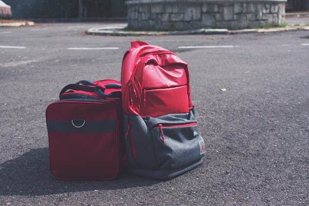 Red backpack and matching bag on asphalt, perfect for travel themes.